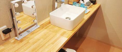 A bathroom with a vanity, mirror, sink, and a black trash bin.