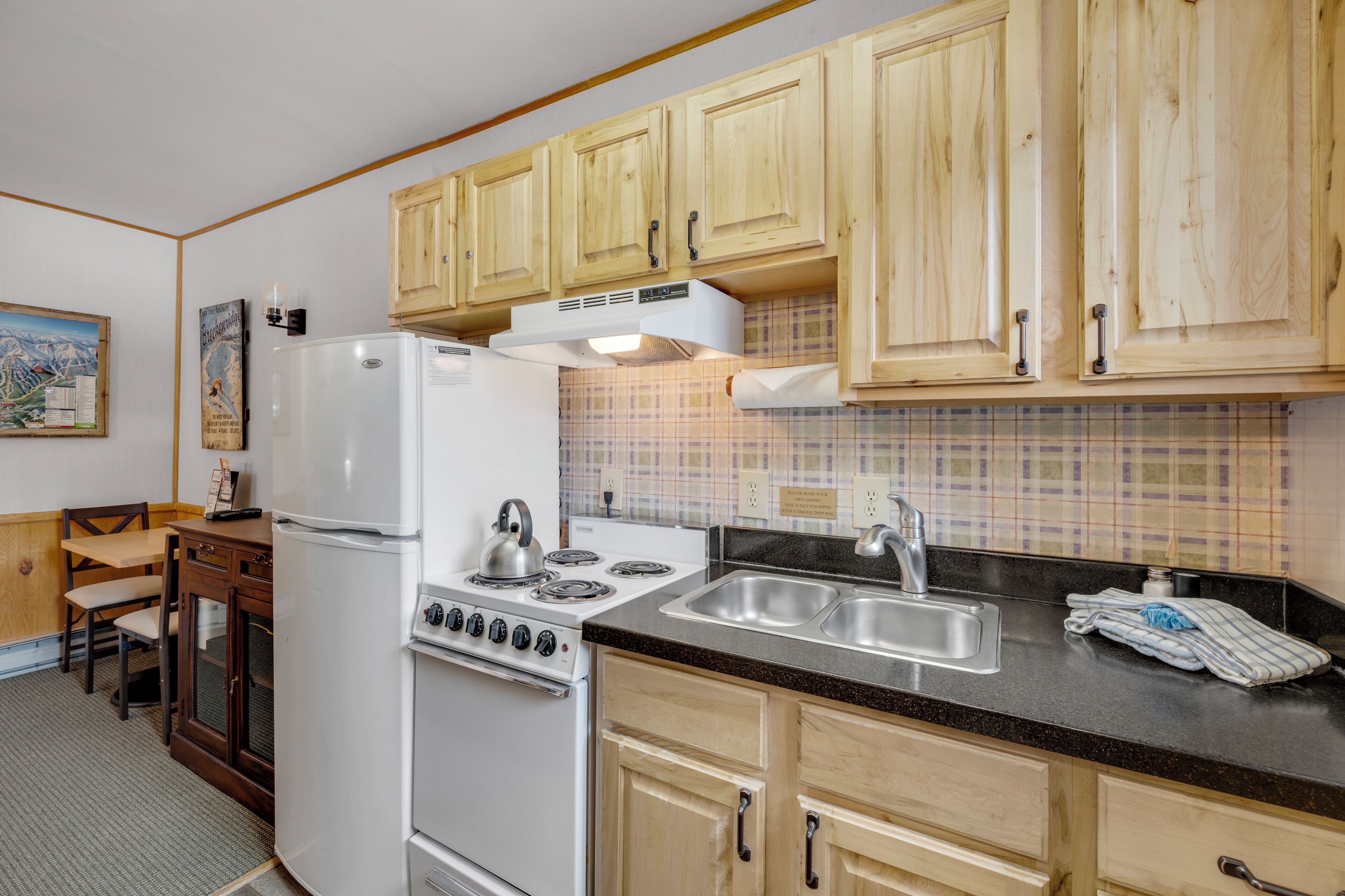 Una cocina con armarios de madera, un refrigerador blanco, una estufa y un lavamanos.