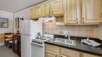 Una cocina con armarios de madera, un refrigerador blanco, una estufa y un lavamanos.