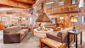A cozy, rustic interior with a fireplace, wooden furniture, and a pool table.
