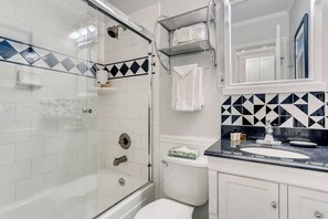 A modern bathroom with a glass-enclosed shower, a white toilet, and a vanity with a sink and mirror.