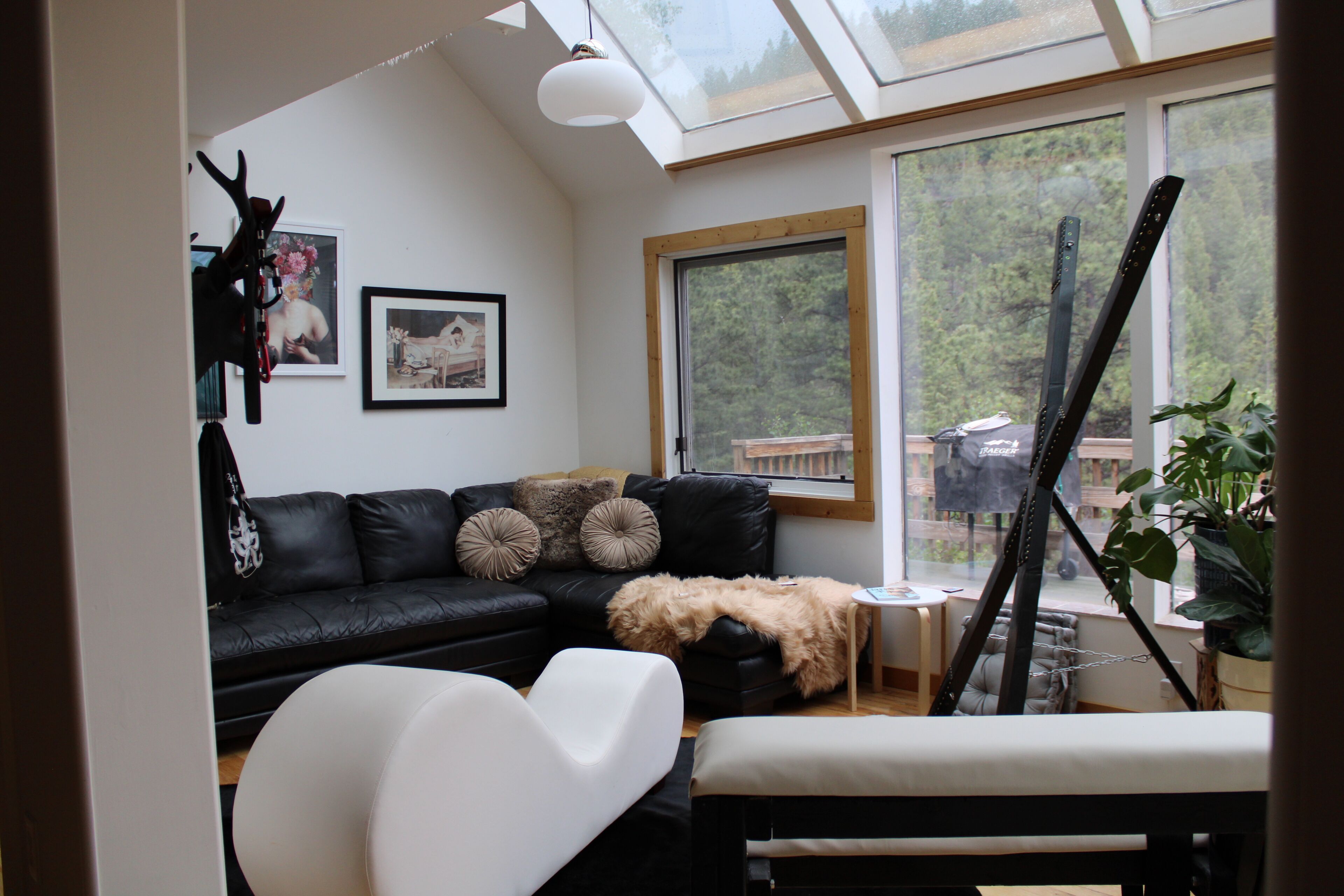 A modern living room with a black leather sofa, white armchair, and a glass ceiling.