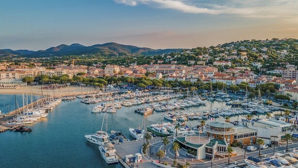 A marina with numerous boats docked, surrounded by residential buildings and a hilly landscape in the background. - METERS FROM THE MEDITERRANEAN AMID ST. TROPEZ & ST. MAXIM (Roquebrune-sur-Argens)