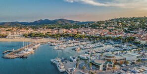 Un port de plaisance où sont amarrés de nombreux bateaux, entouré de bâtiments résidentiels et avec, en arrière-plan, un paysage vallonné.