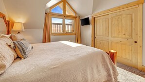 A bedroom with a large bed, a window with curtains, a wooden door, and a television on the wall. - Unbelievable Downtown, Walk Everywhere. Pet Friendly! Private Hot Tub! SCC4 (Breckenridge)