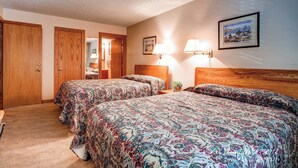 A bedroom with two beds, wooden wardrobes, and a nightstand with a lamp. - Budget Friendly Hotel Lock Off Steps from the Slopes (Breckenridge)