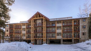A multi-story hotel with a wooden facade, balconies, and a sign indicating it is part of the Langenbaum complex. - Budget Friendly Hotel Lock Off Steps from the Slopes (Breckenridge)