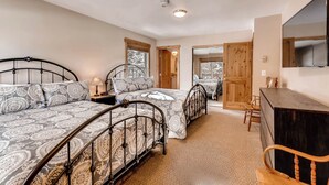 Une chambre avec deux lits, un bureau en bois et un téléviseur fixé au mur.