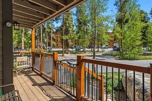 A covered outdoor area with a wooden deck, metal railing, and benches.