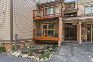 A two-story building with a balcony, stone accents, and a small garden area.
