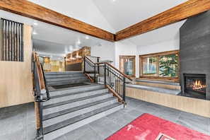 A staircase with wooden beams, a fireplace, and a red rug.
