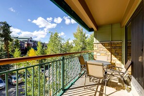 Enjoy the serene view of the surrounding neighborhood from this balcony with a table and two chairs.