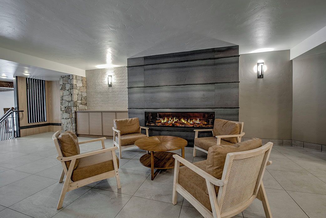 Una sala de estar moderna con chimenea, asientos cómodos y una pared de acento de piedra.