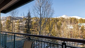 A balcony with a view of a snow-covered mountain, trees, and parked cars. - Ideal Breck Location, Mountain Views, Wi-Fi, Garage Parking TE405 (Breckenridge)