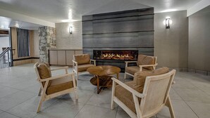Un salon moderne doté d’une cheminée, de sièges confortables et d’un mur d’accent en pierre.
