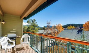 Un balcon avec vue sur les montagnes et les arbres aux couleurs automnales.