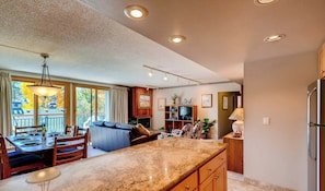 A modern kitchen with a marble countertop, wooden cabinets, and a dining area with a table set for two.