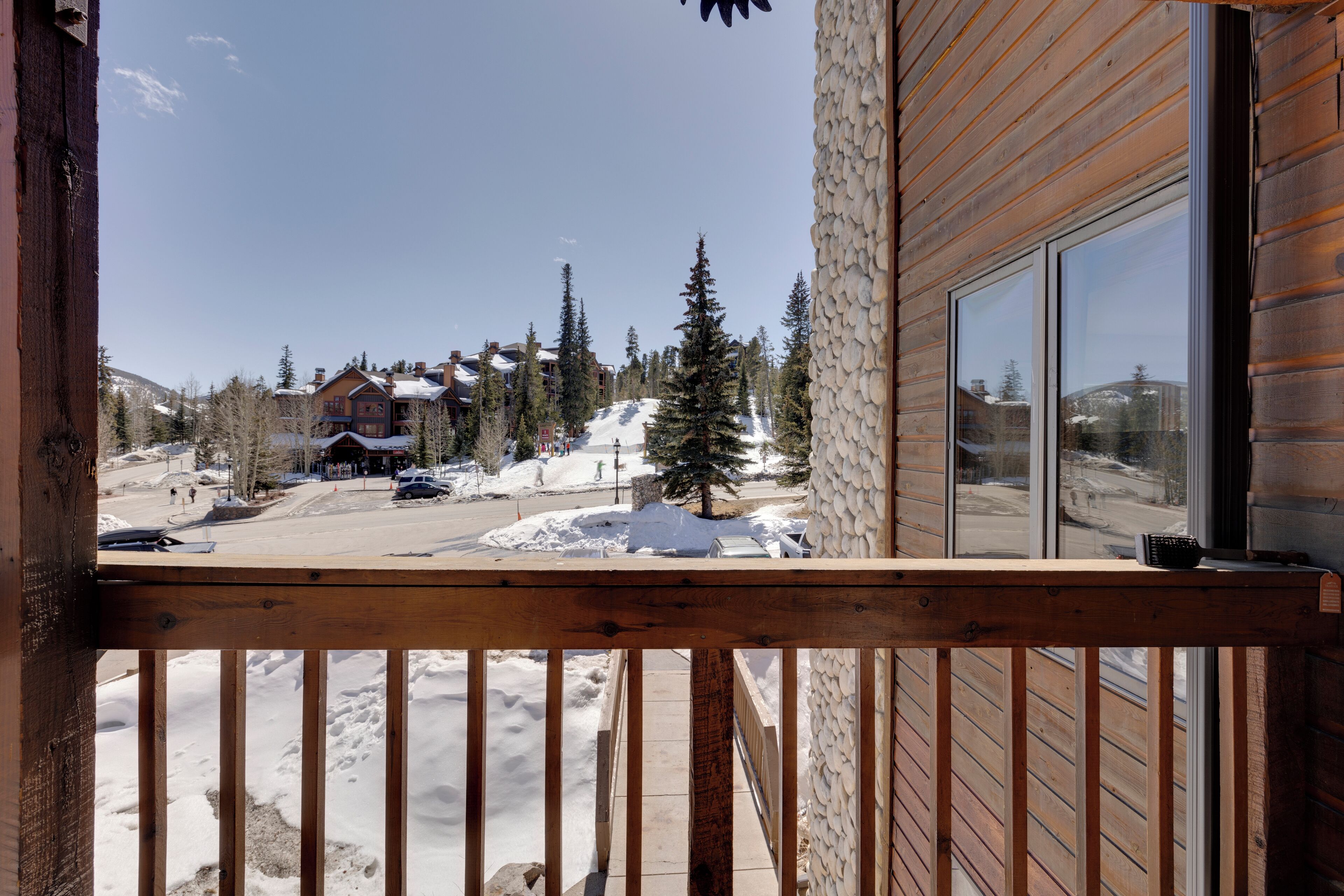 Un balcón de madera con vista a un pueblo nevado, con edificios y árboles.