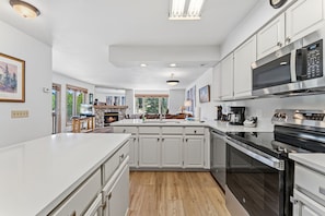 A modern kitchen with white cabinetry, a central island, a built-in oven, and a microwave.