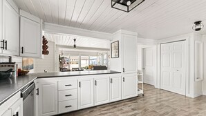 Una cocina amplia con armarios blancos, una isla central y suelo de madera.