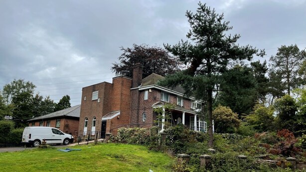 A two-story brick house with a front porch, a white van parked in the driveway, and a well-maintained lawn. - Burleigh House  (Stoke-on-Trent)