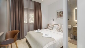 A modern bedroom with a large bed, a chair, a bedside table, and a bathroom visible through an open door. - Ganz Neue Top Villa (Tadini)