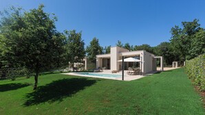 A modern house with a swimming pool, surrounded by a well-maintained lawn and trees. - Ganz Neue Top Villa (Tadini)