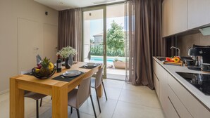 A modern kitchen with a dining area, large windows, and a view of a swimming pool. - Ganz Neue Top Villa (Tadini)