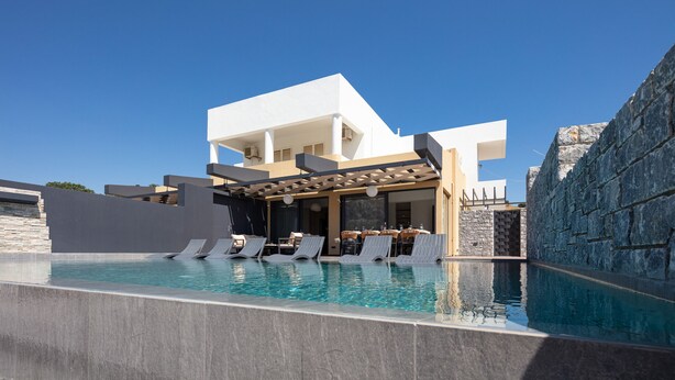 A modern pool area with lounge chairs, a pergola, and a stone wall. - Oasis Serenity,Serene,Nature views,Kids pool (Agouseliana)