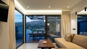A modern living room with a sofa, a wooden coffee table, and a dining area with chairs and a table. - Oasis Serenity,Serene,Nature views,Kids pool (Agouseliana)