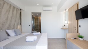 A modern hotel room with a large bed, a TV, a wooden side table, and a shower area. - Oasis Serenity,Serene,Nature views,Kids pool (Agouseliana)