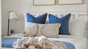 A bed with a white headboard, two blue pillows, and a woven blanket. - Smith`s Church House | 1903 | Fireplace | Iconic (Wilmer)