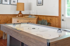 Una mesa de billar con una lámpara, una mesita con un vaso y una planta.
