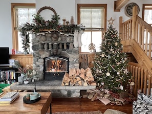 A cozy living room with a stone fireplace, a Christmas tree, and a wooden staircase. - Smith`s Church House | 1903 | Fireplace | Iconic (Wilmer)