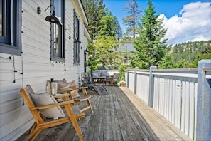 A wooden deck with outdoor furniture, a white building with black-framed windows, and a white picket fence. - Smith`s Church House | 1903 | Fireplace | Iconic (Wilmer)