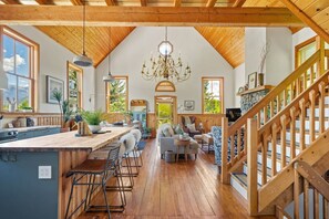 A spacious kitchen with wooden beams, a large island with bar stools, and a view of the outdoors. - Smith`s Church House | 1903 | Fireplace | Iconic (Wilmer)