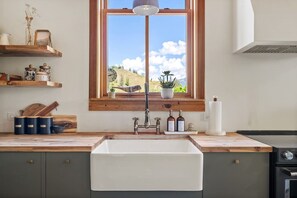 Eine Küche mit großem Fenster, Holzböden, Spüle und Herd.