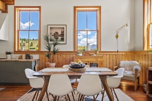 A dining area with a wooden table, four chairs, a vase, and a painting on the wall. - Smith`s Church House | 1903 | Fireplace | Iconic (Wilmer)