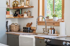 A kitchen with wooden shelves, a window with a clock, and a sink with a faucet. - Smith`s Church House | 1903 | Fireplace | Iconic (Wilmer)