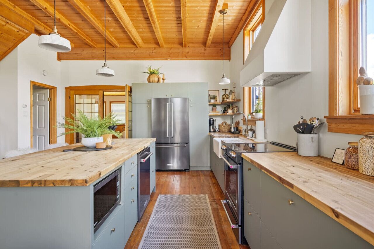 Eine moderne Küche mit Holzbalken, Edelstahlgeräten und einer Holzausziehtafel.