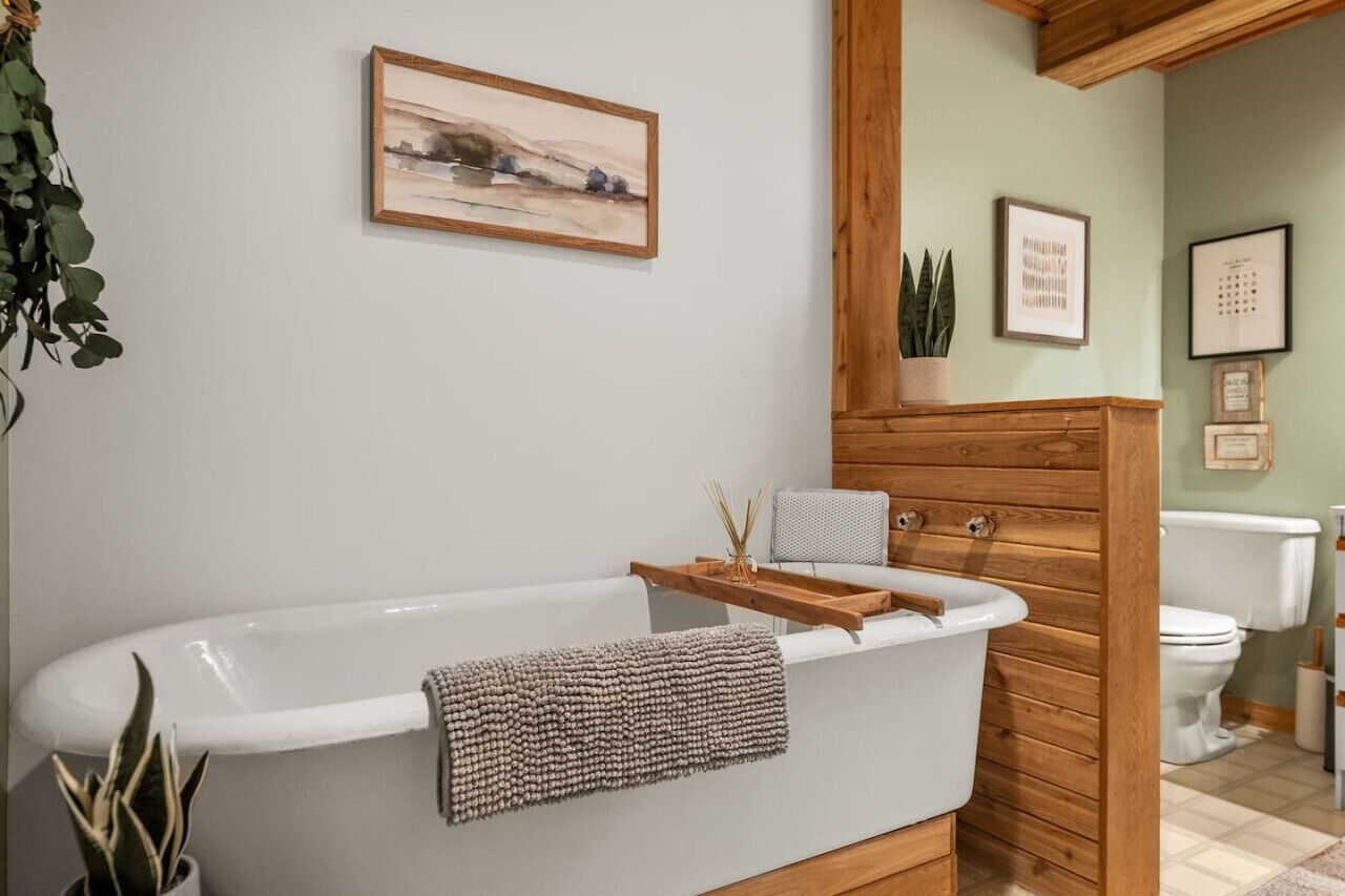 Ein modernes Badezimmer mit einer freistehenden Badewanne, Holzvertäfelung und einem gerahmten Kunstwerk an der Wand.