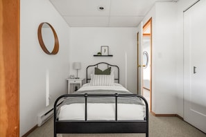 A bedroom with a bed, bedside table, lamp, and a door leading to another room. - Smith`s Church House | 1903 | Fireplace | Iconic (Wilmer)