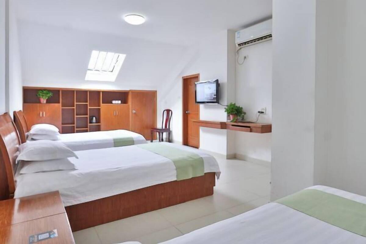 Ein Hotelzimmer mit zwei Betten, einem Schreibtisch, einem Fernseher und einem Oberlicht.