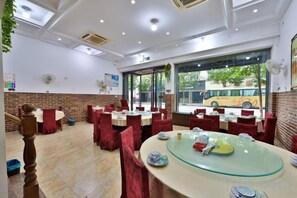 A restaurant with tables and chairs, a staircase, and a view of a bus outside.