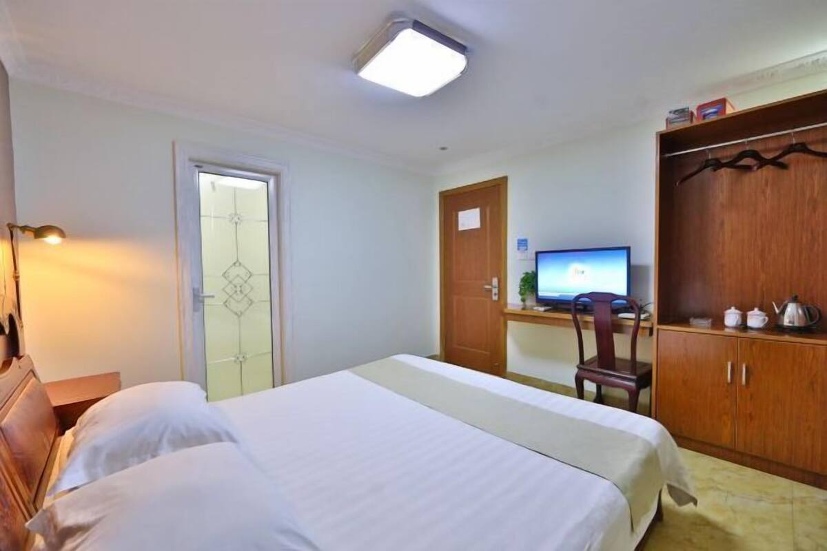 Ein Hotelzimmer mit einem Bett, einem Schreibtisch mit Computer, einem Kleiderschrank und einer Tür.