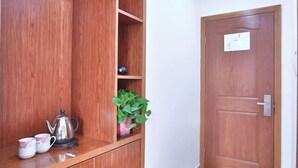 A wooden cabinet with a kettle and cups, a potted plant, and a door with a sign. - Wuzhen Xiangli Xiangqin Homestay (Tongxiang)