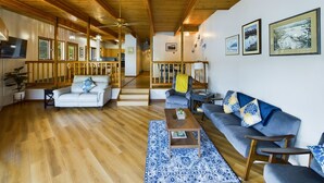A spacious living area with wooden floors and ceiling, a sofa set, a coffee table, and a staircase leading to another level. - Stunning Oceanfront Home w/ Mountain Views! (Juneau)