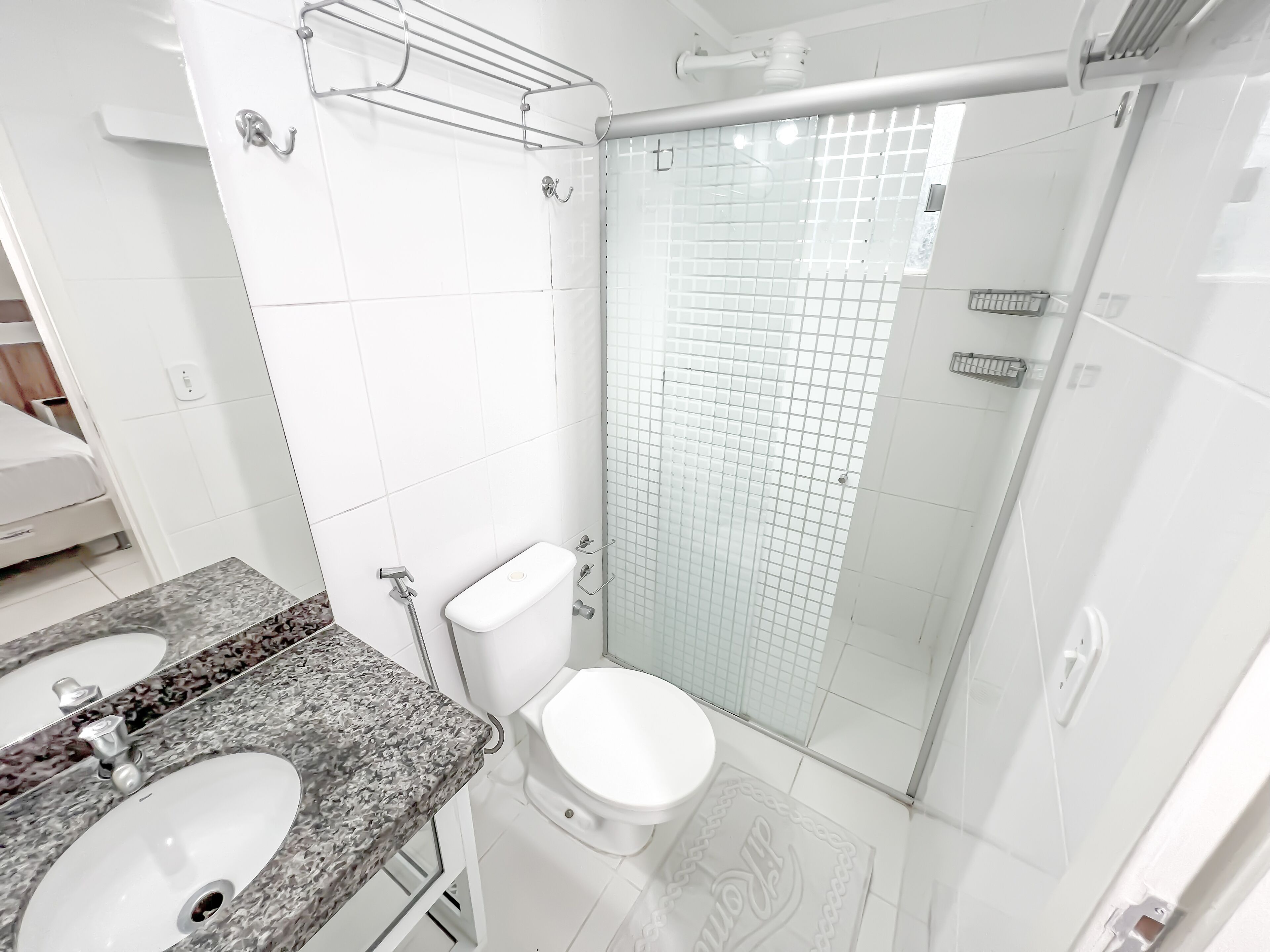 Un baño moderno con dos lavamanos, un inodoro y una cabina de ducha de vidrio.