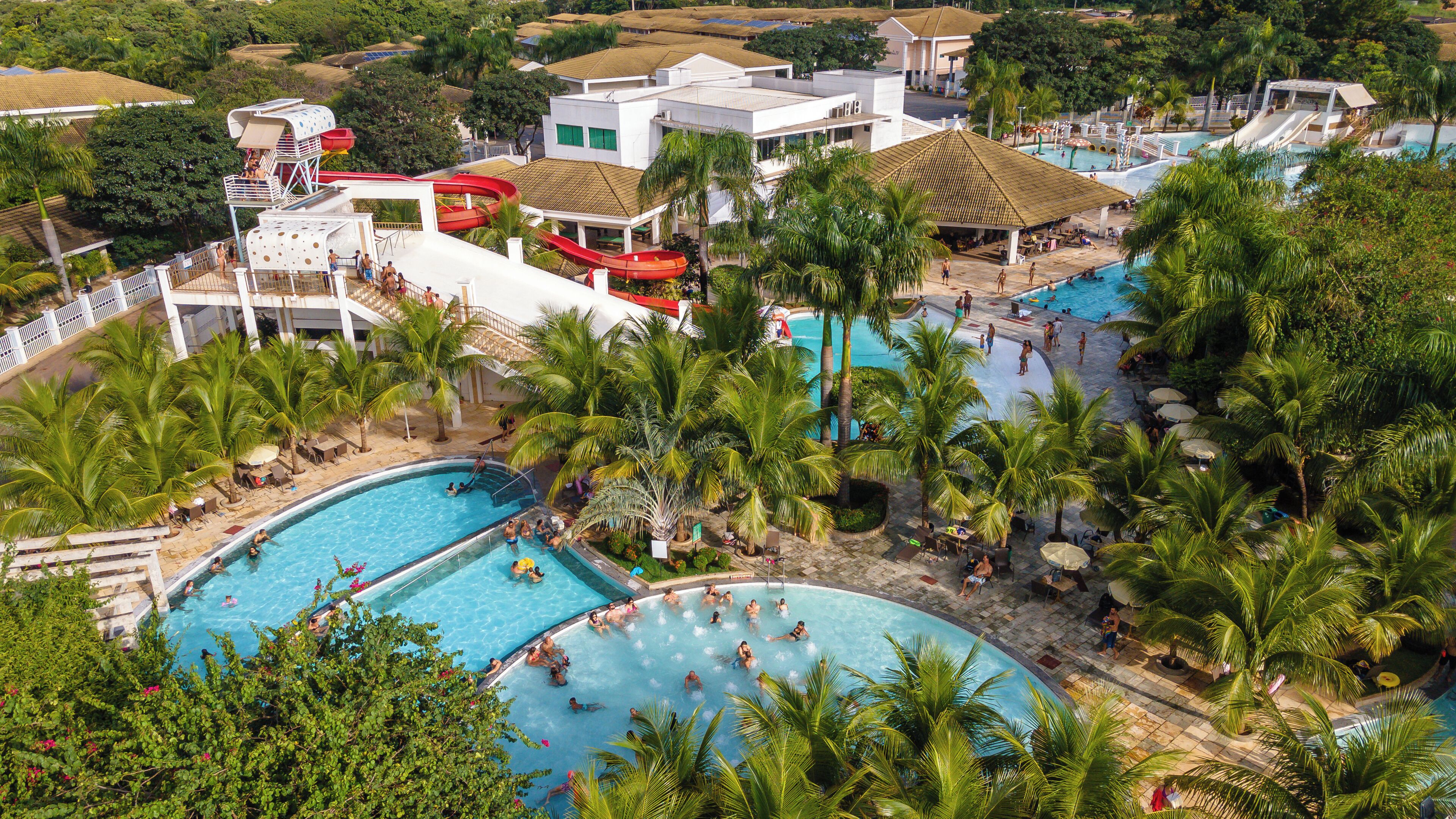 Un resort con varias piscinas rodeado de palmeras y un tobogán de agua.