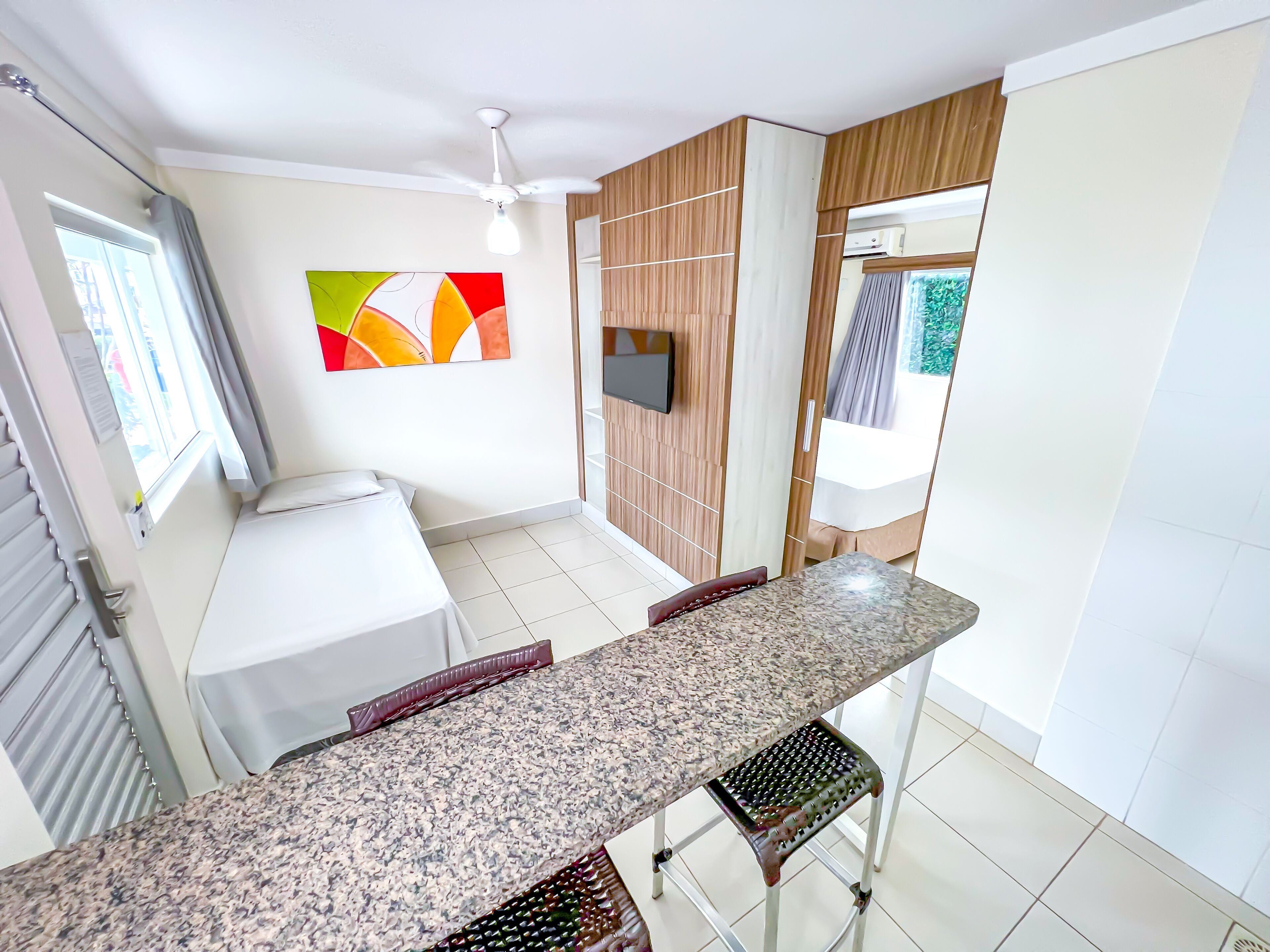 A modern kitchen with a granite countertop, a built-in oven, and a TV mounted on the wall.